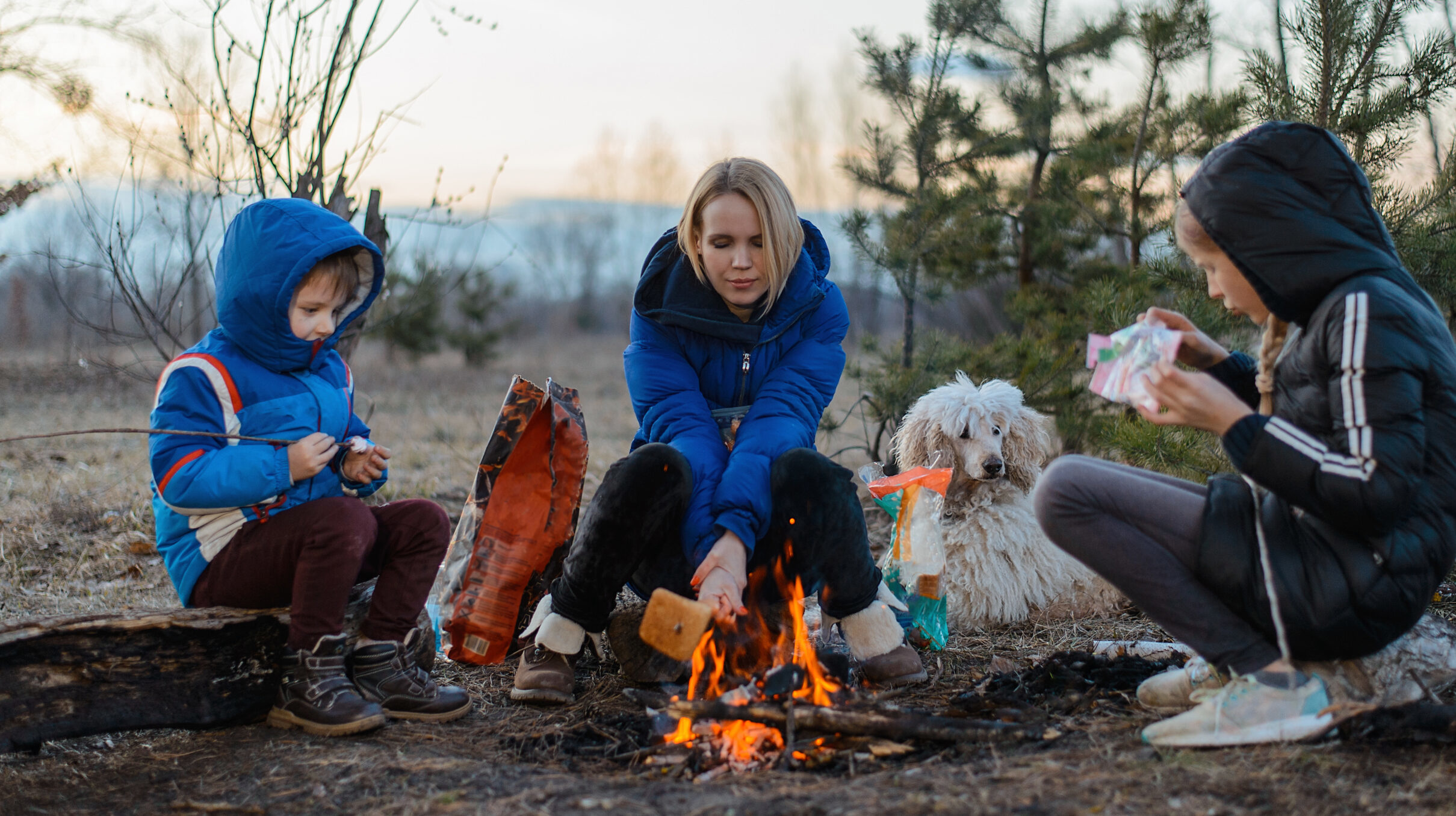 Adult and two children sitting around camp fire